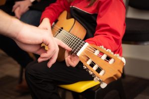 Lehrer unterrichtet Kind an Gitarre